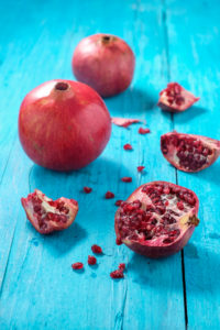 Whole and sliced pomegranates on turquoise wooden table Whole and sliced pomegranates on turquoise wooden table